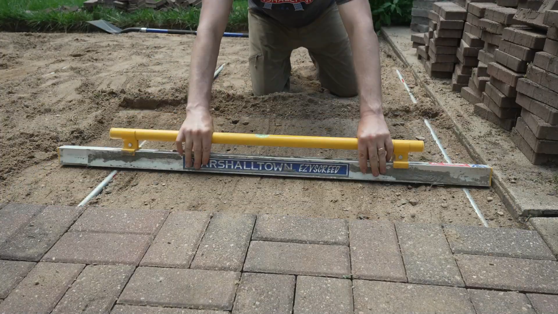man using ezyscreed to screed the sand